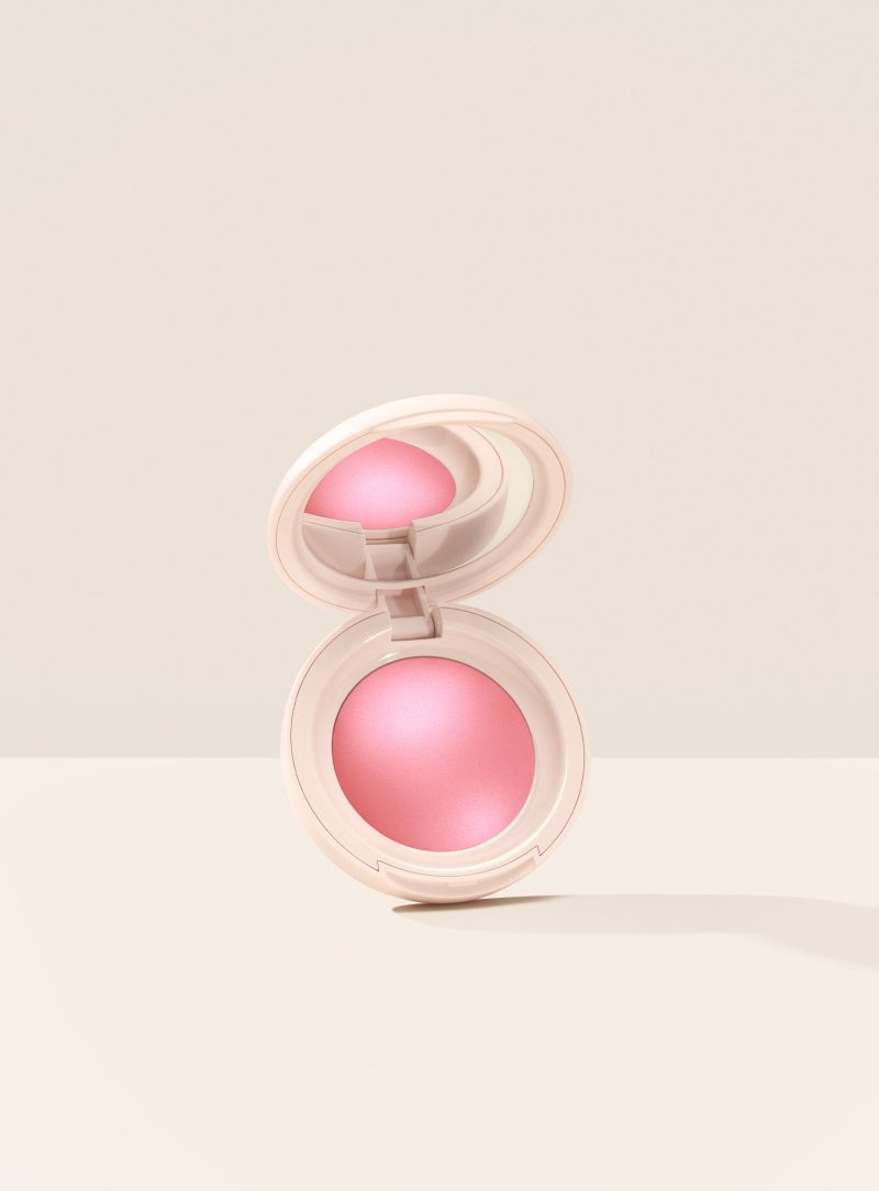 Happy| Rare Beauty's Soft Pinch Luminous Powder Blush in the shade Happy hovering, opened, against a neutral background.