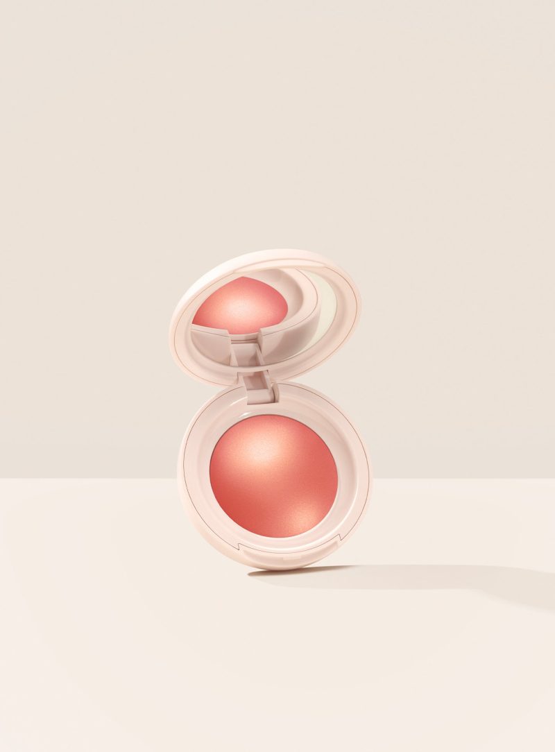 Joy| Rare Beauty's Soft Pinch Luminous Powder Blush in the shade Joy hovering, opened, against a neutral background.